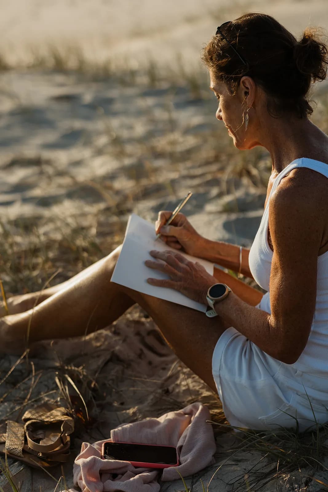 Dana Eden writing in a notebook in the dunes
