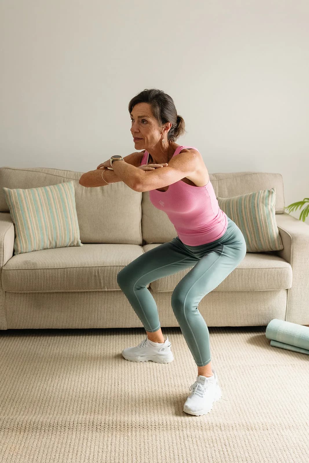 Dana Eden doing a bodyweight squat in her lounge room