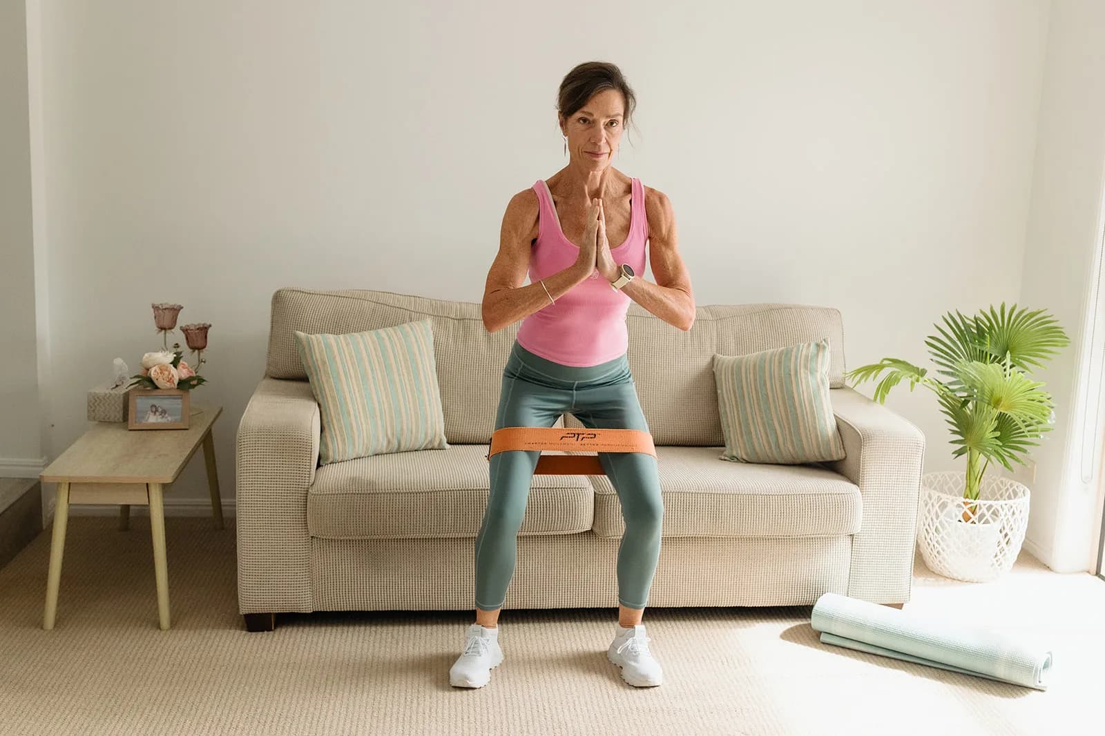 Dana Eden leading a banded squat, facing the camera