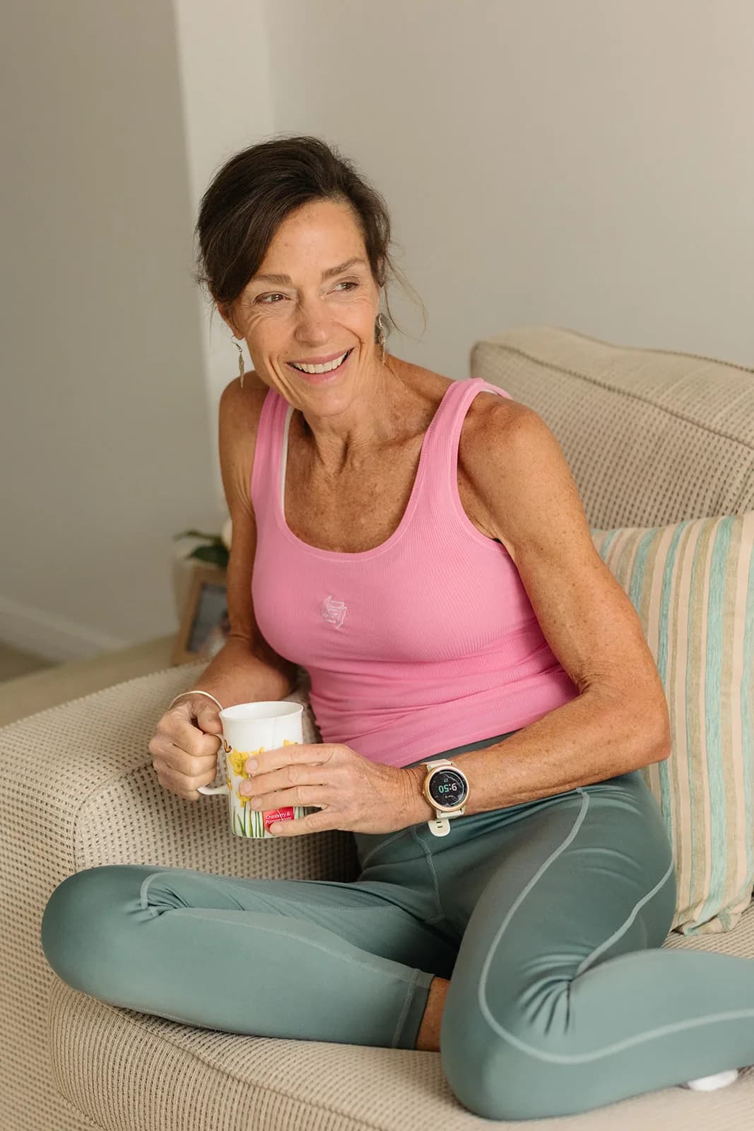 Dana Eden on the couch with a cup of tea, smiling