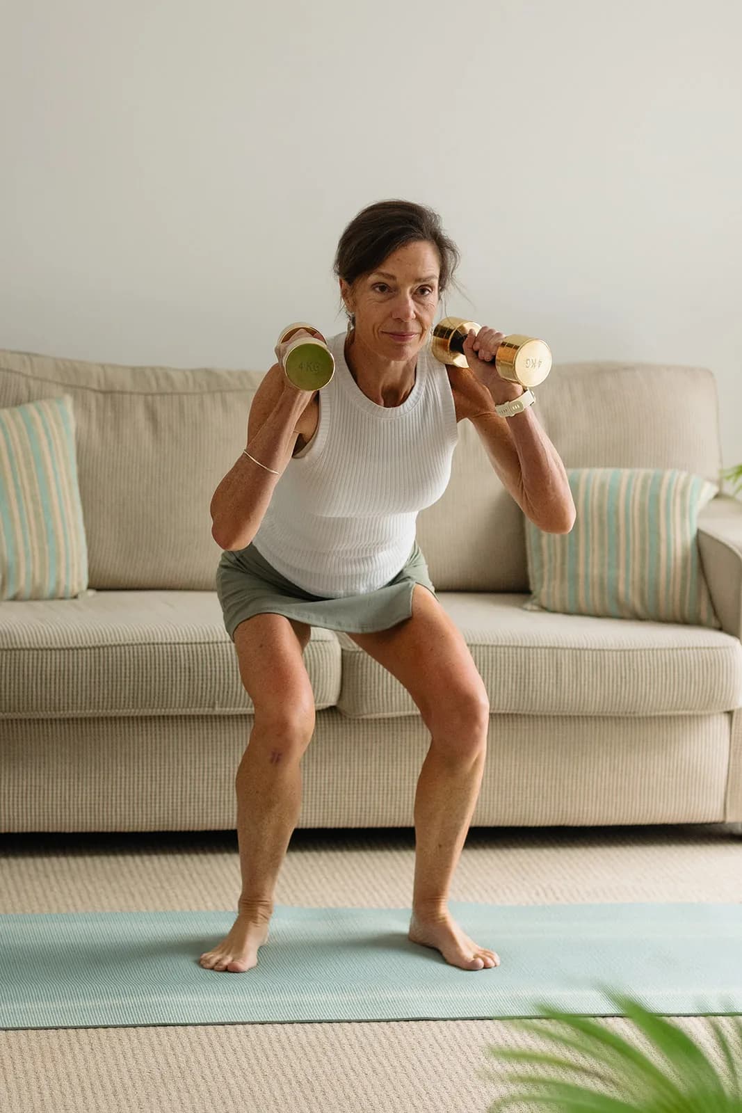 Dana Eden doing a dumbbell squat in her lounge room