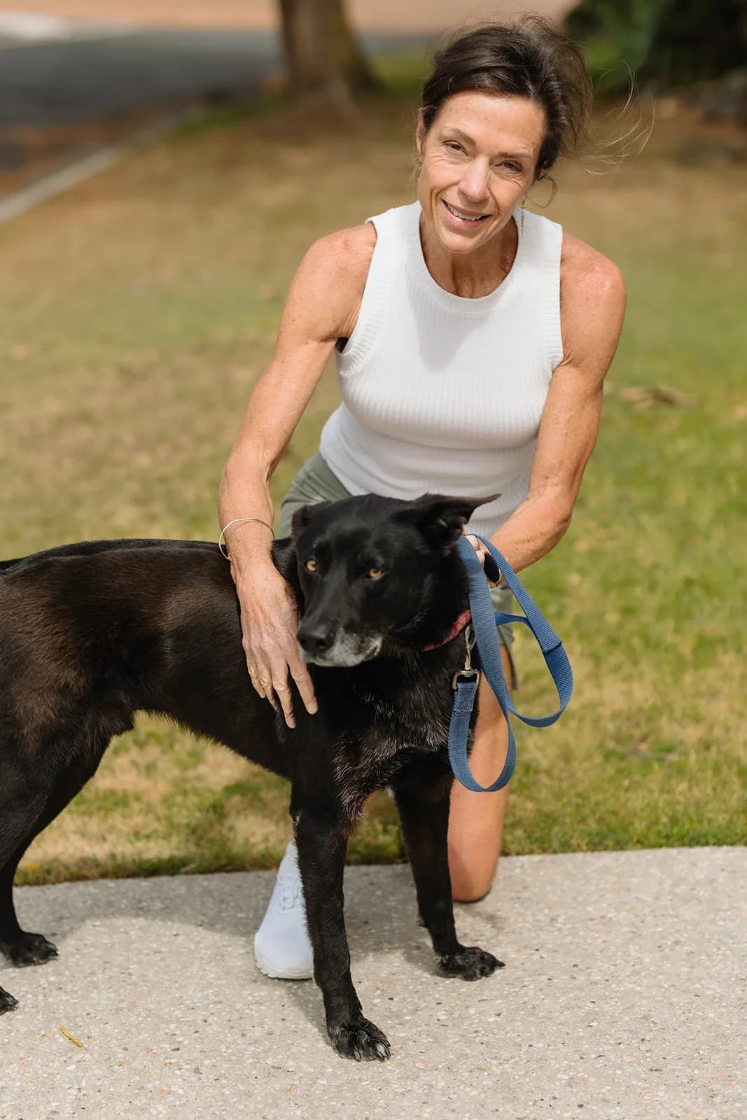 Dana Eden kneeling on the lawn with her dog