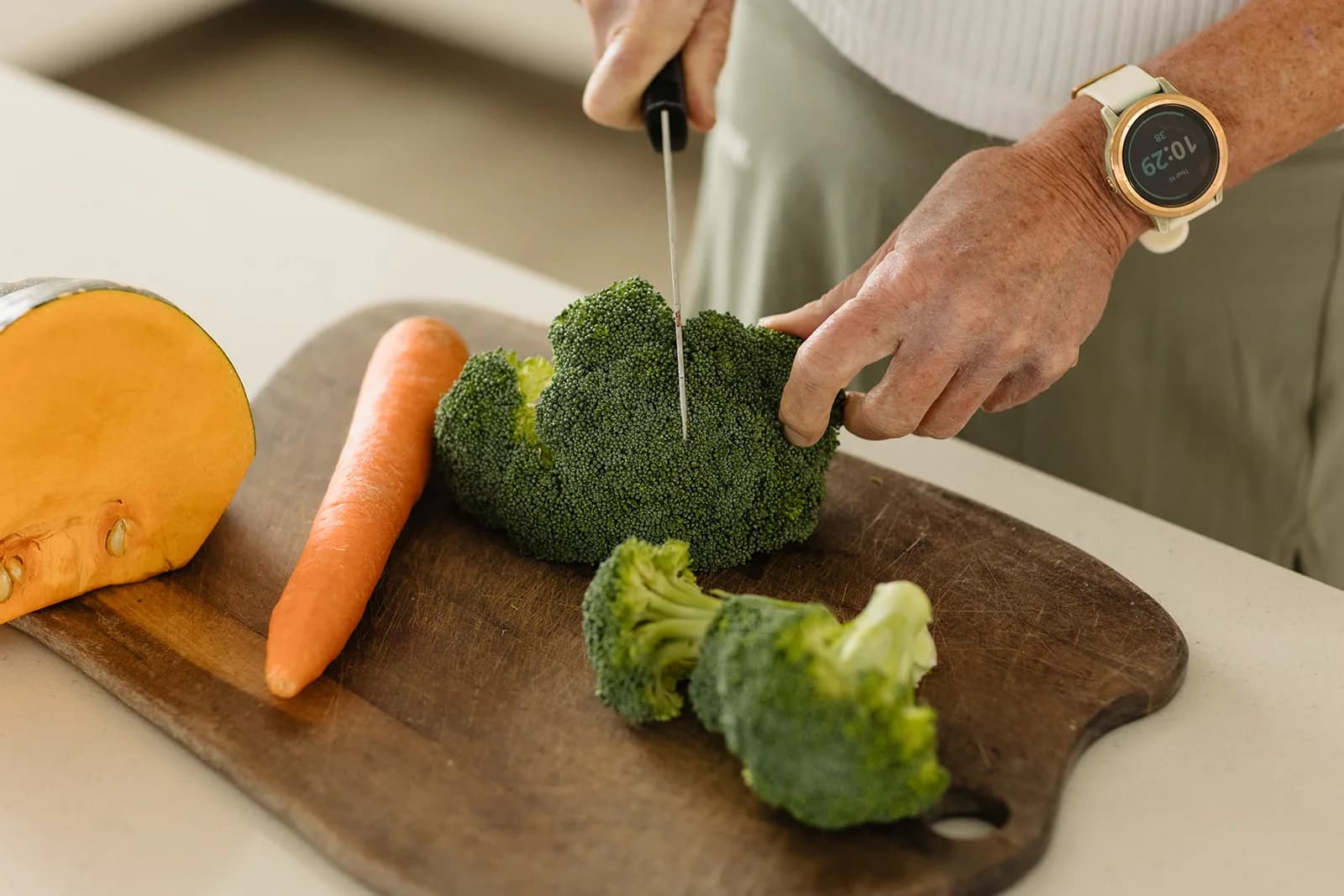 Broccoli, carrot and pumpkin being chopped on a wooden board