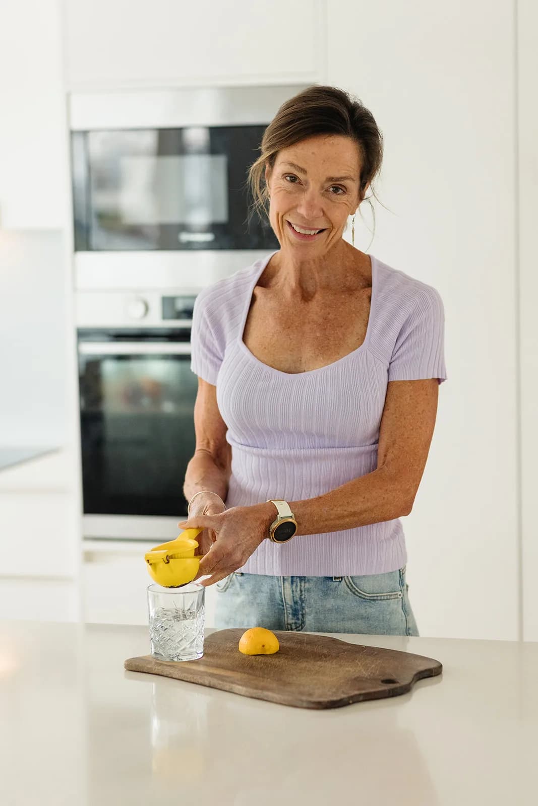 Dana Eden squeezing a lemon in her kitchen, smiling